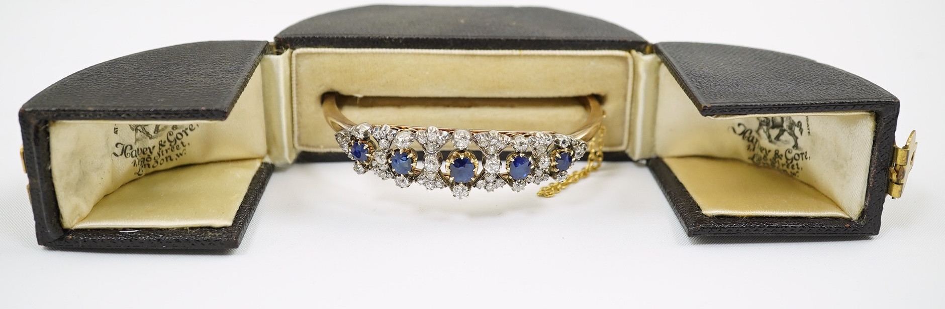 A late Victorian gold, sapphire and diamond cluster hinged bangle